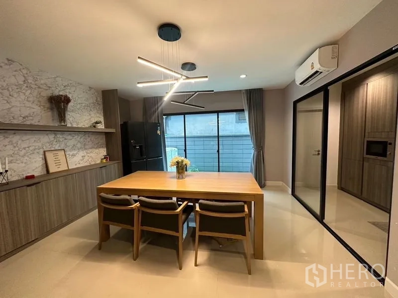 Townhouse for sale in Saphan Sung, Bangkok - Dining room with contemporary pendant light, wood table and sliding doors to kitchen.