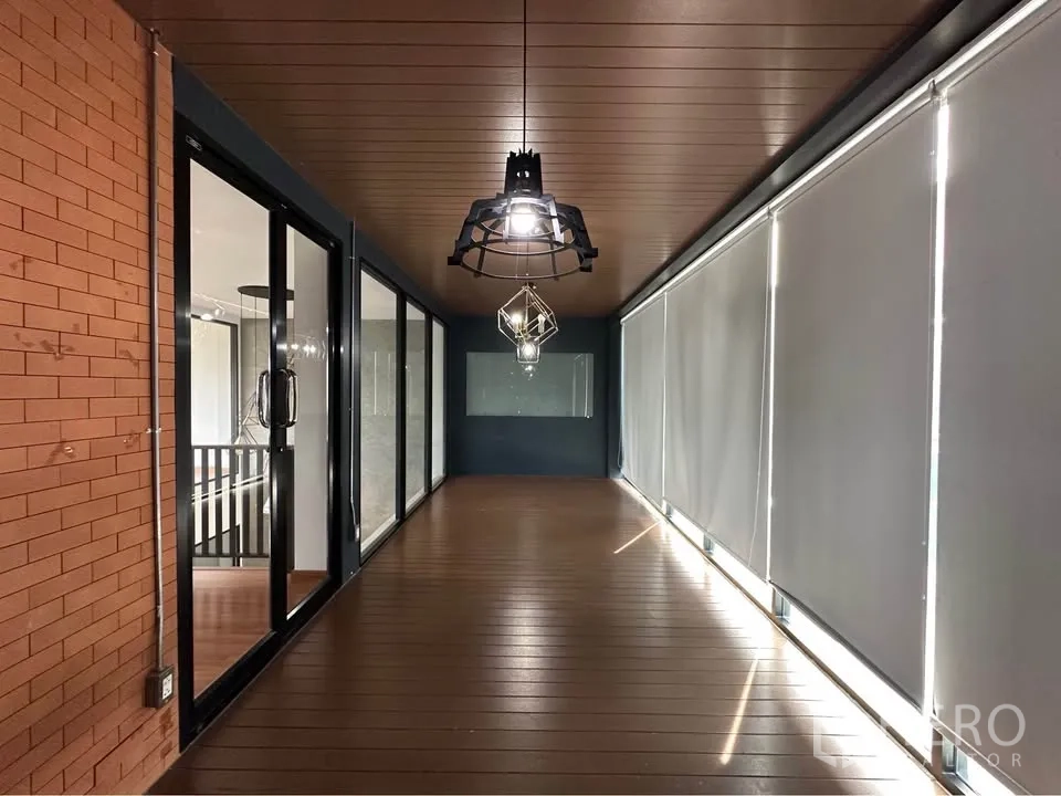 Townhouse for rent in Pak Kret, Nonthaburi - Enclosed balcony corridor with pendant lights, wood ceiling, and roller blinds.