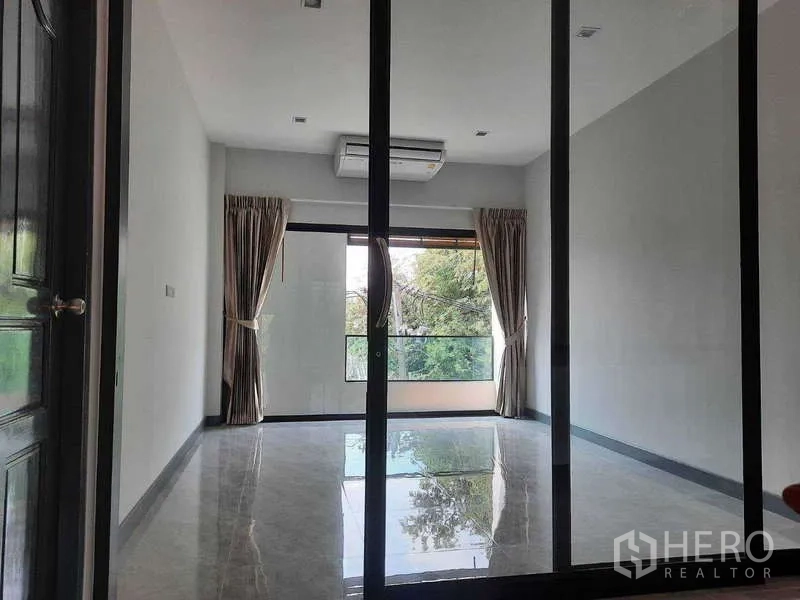 Home Office for rent in Huai Khwang, Bangkok - Glass-partitioned room facing a balcony with green treetop views.