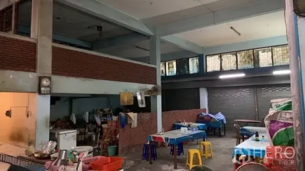Shophouse for sale in Khlong Toei, Bangkok - Open-plan ground floor with high ceilings, brick half-walls and multiple shuttered shopfronts.