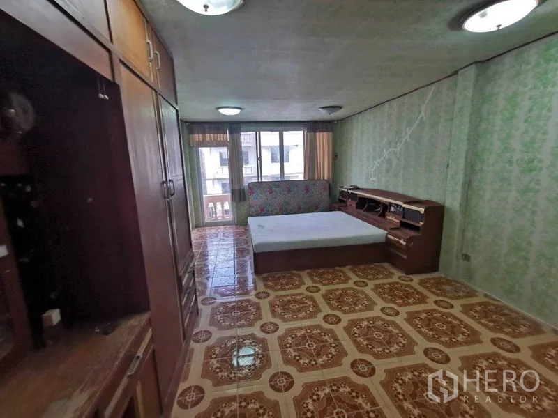 Shophouse for rent in Suan Luang, Bangkok - Large bedroom with balcony windows, wardrobes and patterned floor tiles.