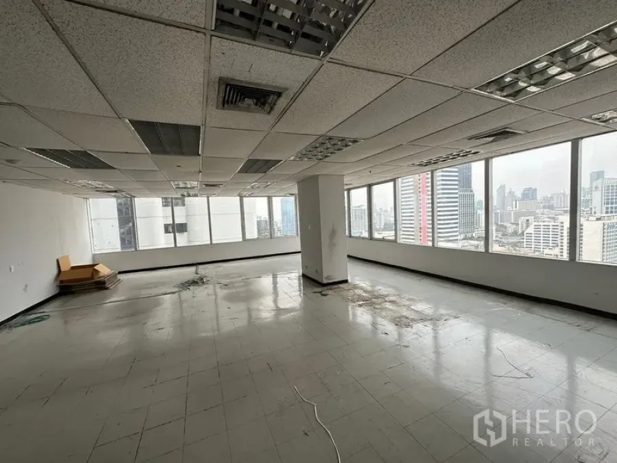 Office Space for rent in Chatuchak, Bangkok - Spacious corner office with grid ceiling lighting and panoramic urban views through wraparound windows.