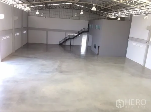 Factory for sale in Bang Sao Thong, Samut Prakan - Spacious warehouse hall with polished concrete floor, steel truss roof and staircase to offices.