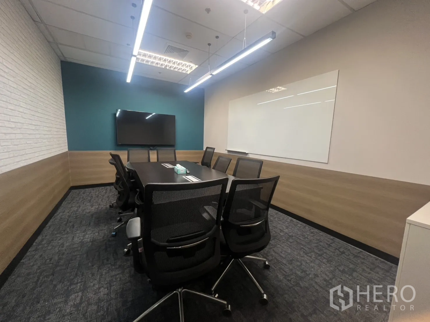 办公空间 出租在Huai Khwang, Bangkok - 会议室配长桌、网面座椅、壁挂电视与大白板，线性灯光。