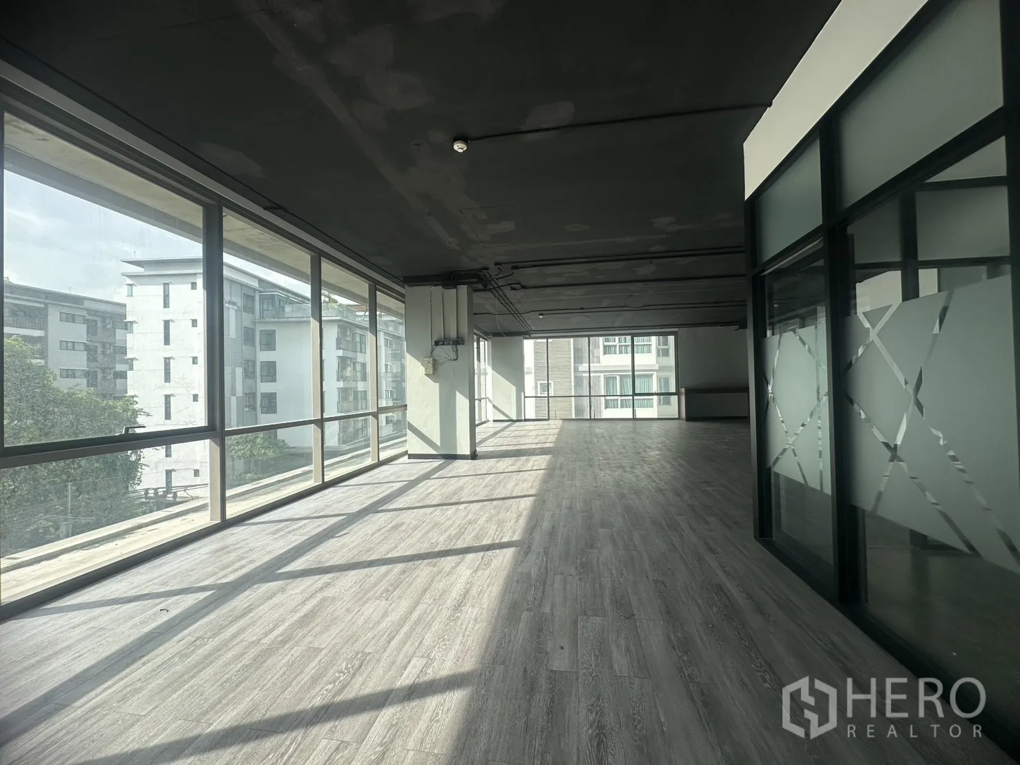 Office Space for rent in Khlong Toei, Bangkok - Sunlit open‑plan office with floor‑to‑ceiling windows and grey vinyl floors in Khlong Toei.