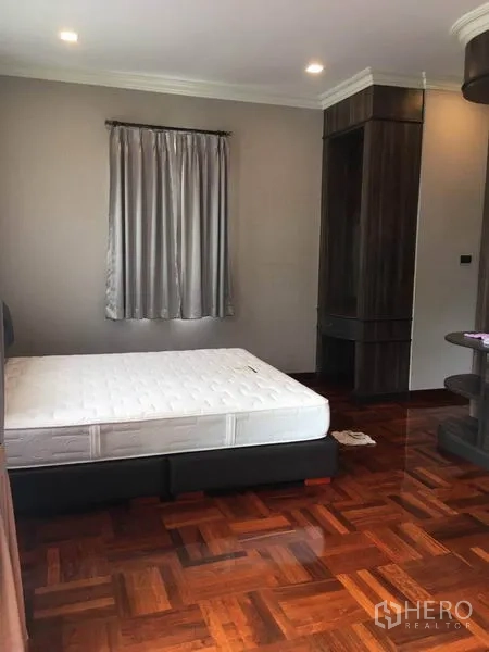 Detached House for rent in Khlong Toei, Bangkok - Guest bedroom with bed, curtains and parquet flooring.