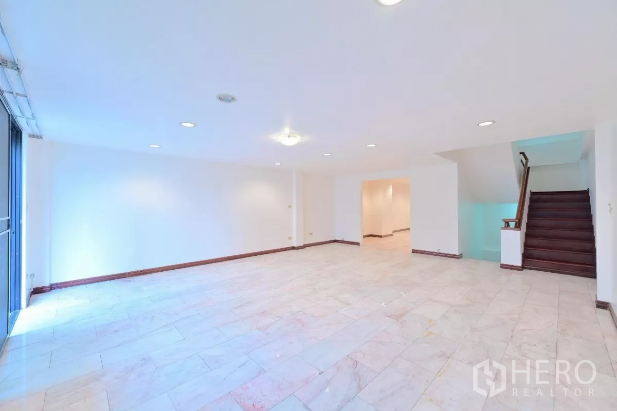 Townhouse for sale in Watthana, Bangkok - Large multipurpose room with white tiled floor, recessed lighting, and stair access.
