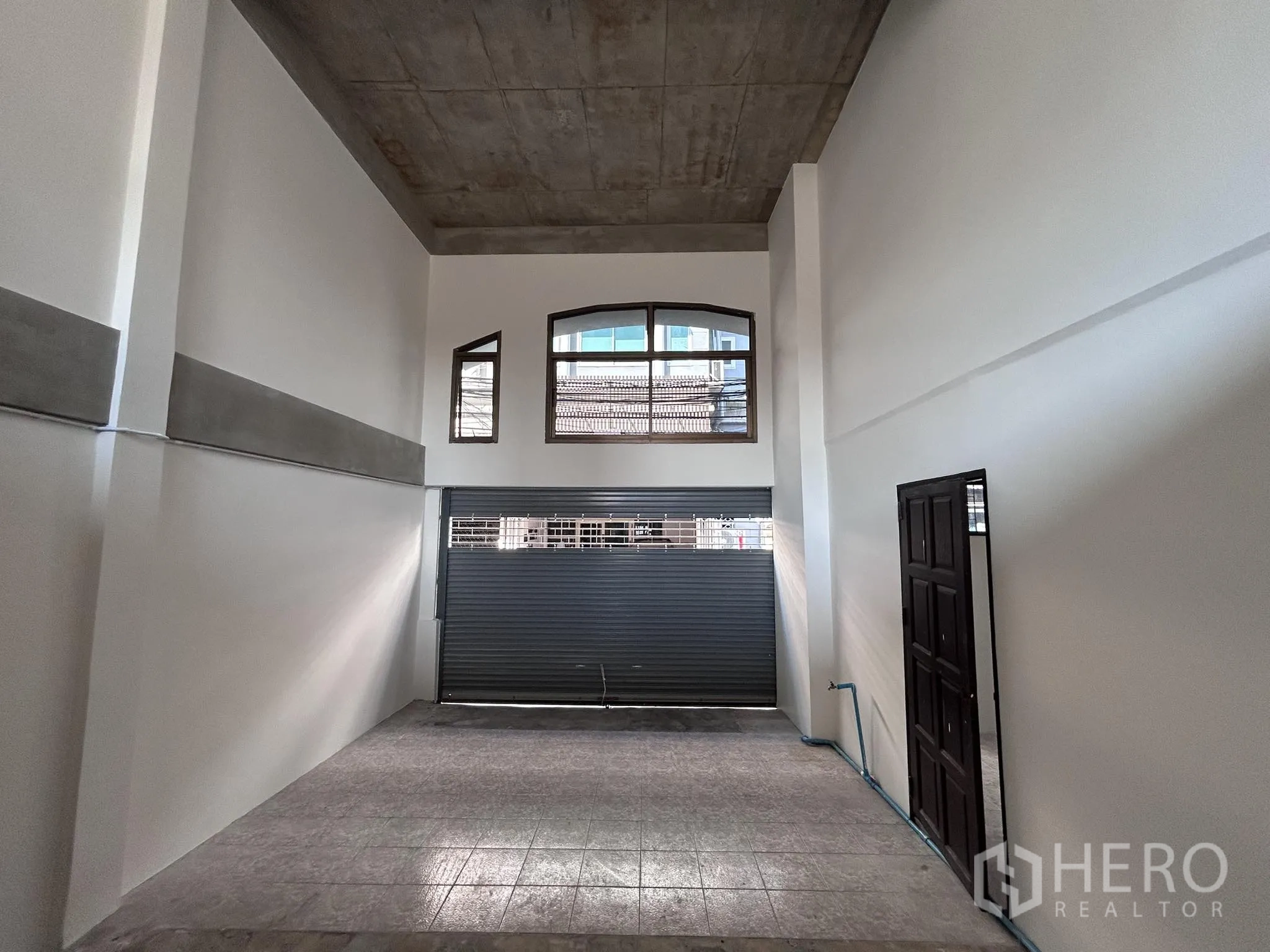 Home Office for rent or sale in Watthana, Bangkok - Ground-floor open space with very high ceiling and metal roller shutter.