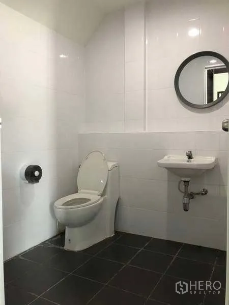 Warehouse for rent in Bang Phli, Samut Prakan - Clean tiled bathroom with toilet, sink and round mirror.