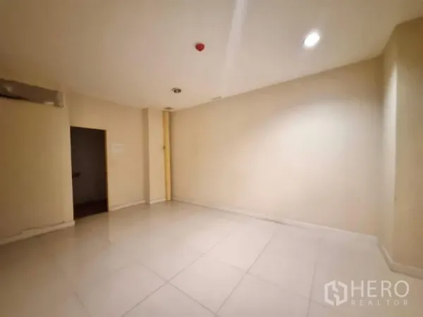 Shophouse for rent in Watthana, Bangkok - Empty beige room with tiled floor and recessed ceiling lights, ideal as an office or treatment room.