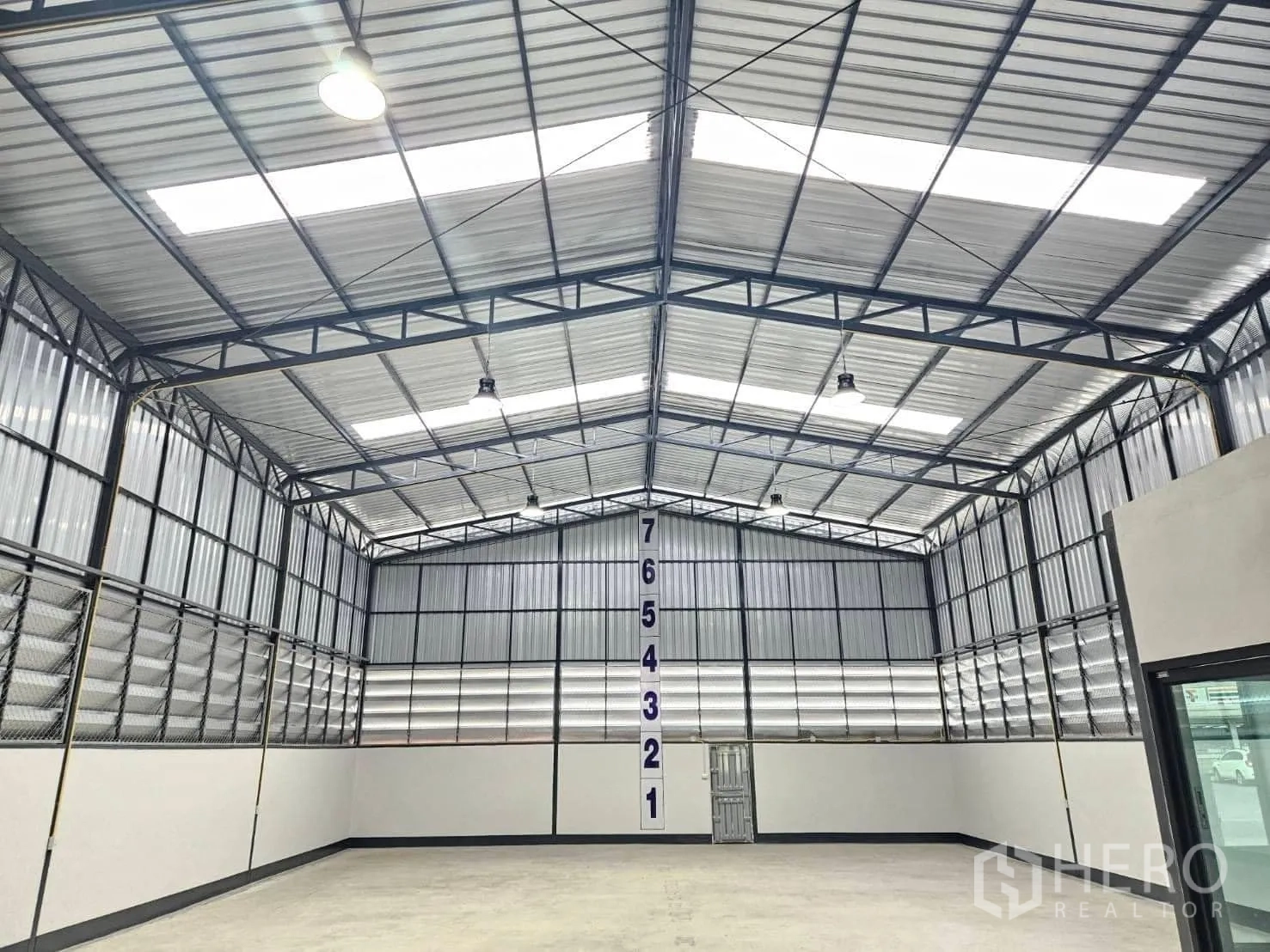 Warehouse for rent in Lam Luk Ka, Pathum Thani - Close-up of roof trusses and skylights with height markers inside the warehouse.