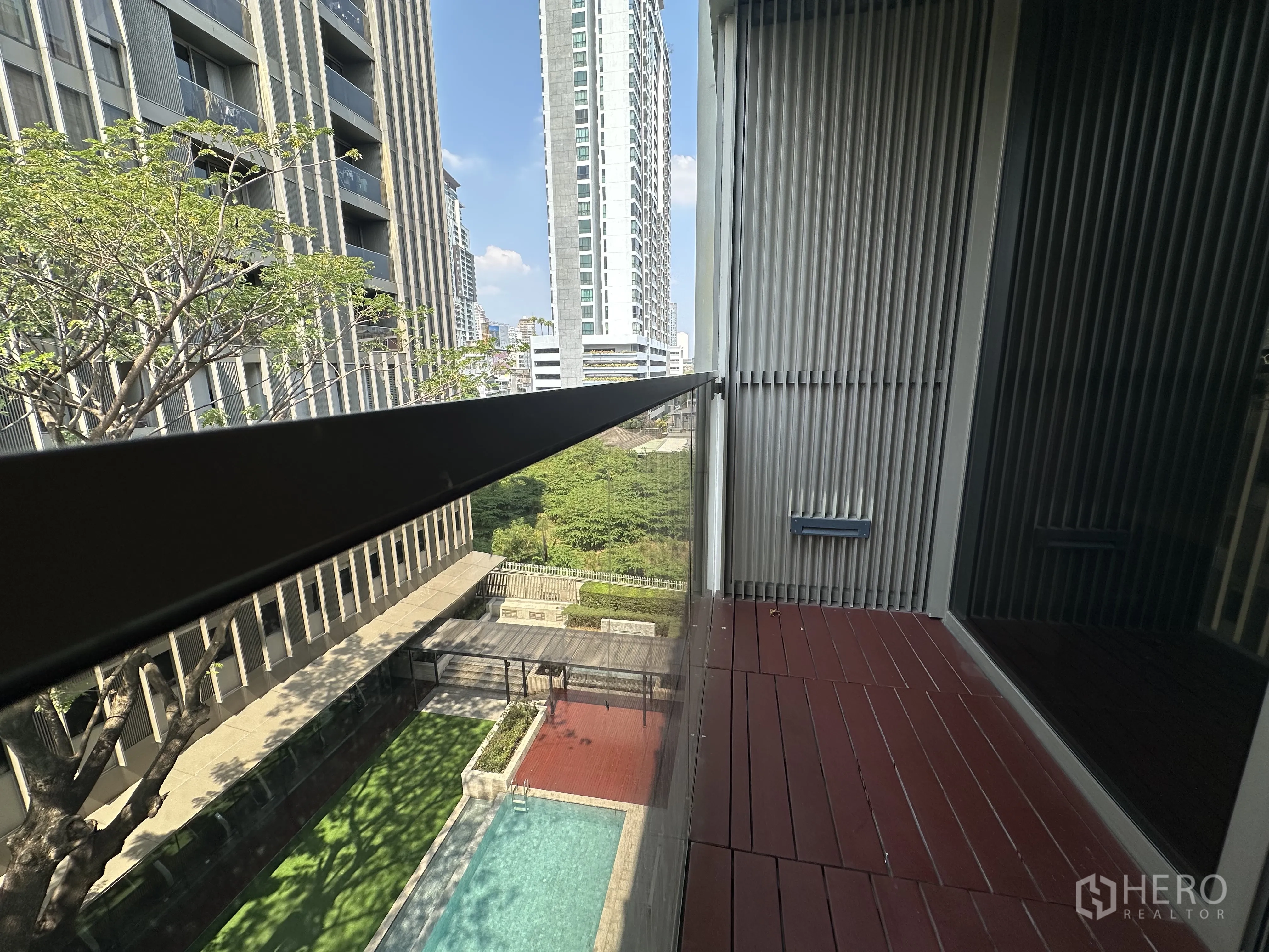 Condominium for rent in Khlong Toei, Bangkok - Private balcony with wood decking overlooking the pool and nearby buildings.
