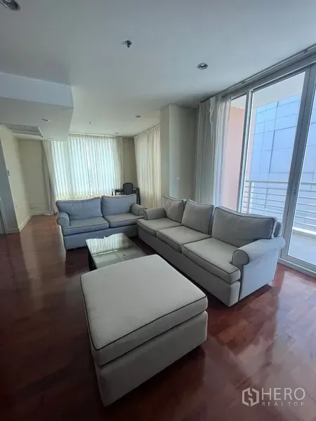 Condominium for rent in Khlong Toei, Bangkok - Living area with two sofas, coffee table and sliding doors opening to a balcony in a Bangkok condo.