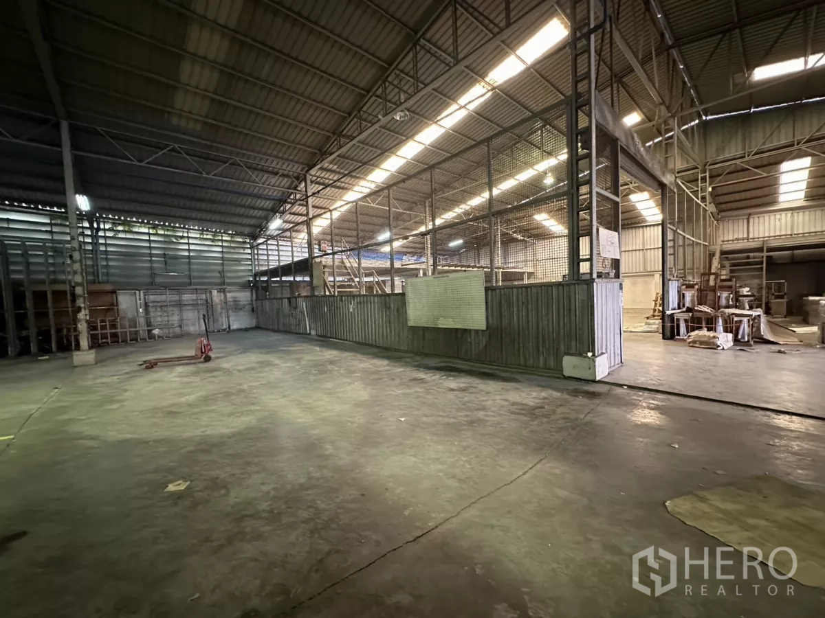 Warehouse for rent in Yan Nawa, Bangkok - Open storage area with mesh‑fenced secure section and steel roof structure.