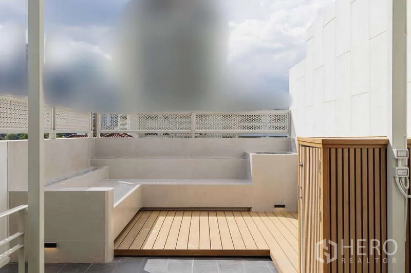 Townhouse for rent or sale in Watthana, Bangkok - Rooftop lounge area with built-in bench seating and wood deck platform.