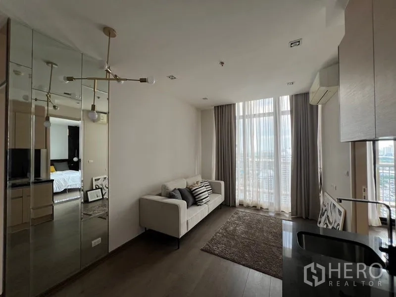 Condominium for sale - Sunny living room with white sofa and panoramic full-height windows.