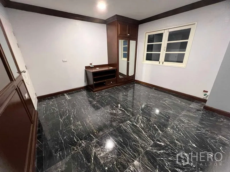 Detached House for sale in Bang Na, Bangkok - Bedroom with polished black marble floor and built-in wooden wardrobe.