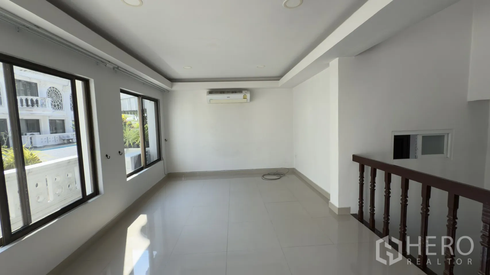 Townhouse for rent in Watthana, Bangkok - Living room view toward the staircase featuring wide windows and an air conditioner.