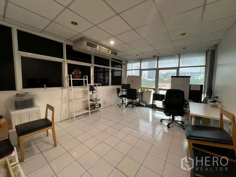 Shophouse for rent or sale in Khlong Toei, Bangkok - Bright office corner with desks, chairs and wide windows overlooking the street.