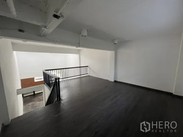 Retail Space for rent in Watthana, Bangkok - Mezzanine level with black metal railing overlooking the double-height retail area.