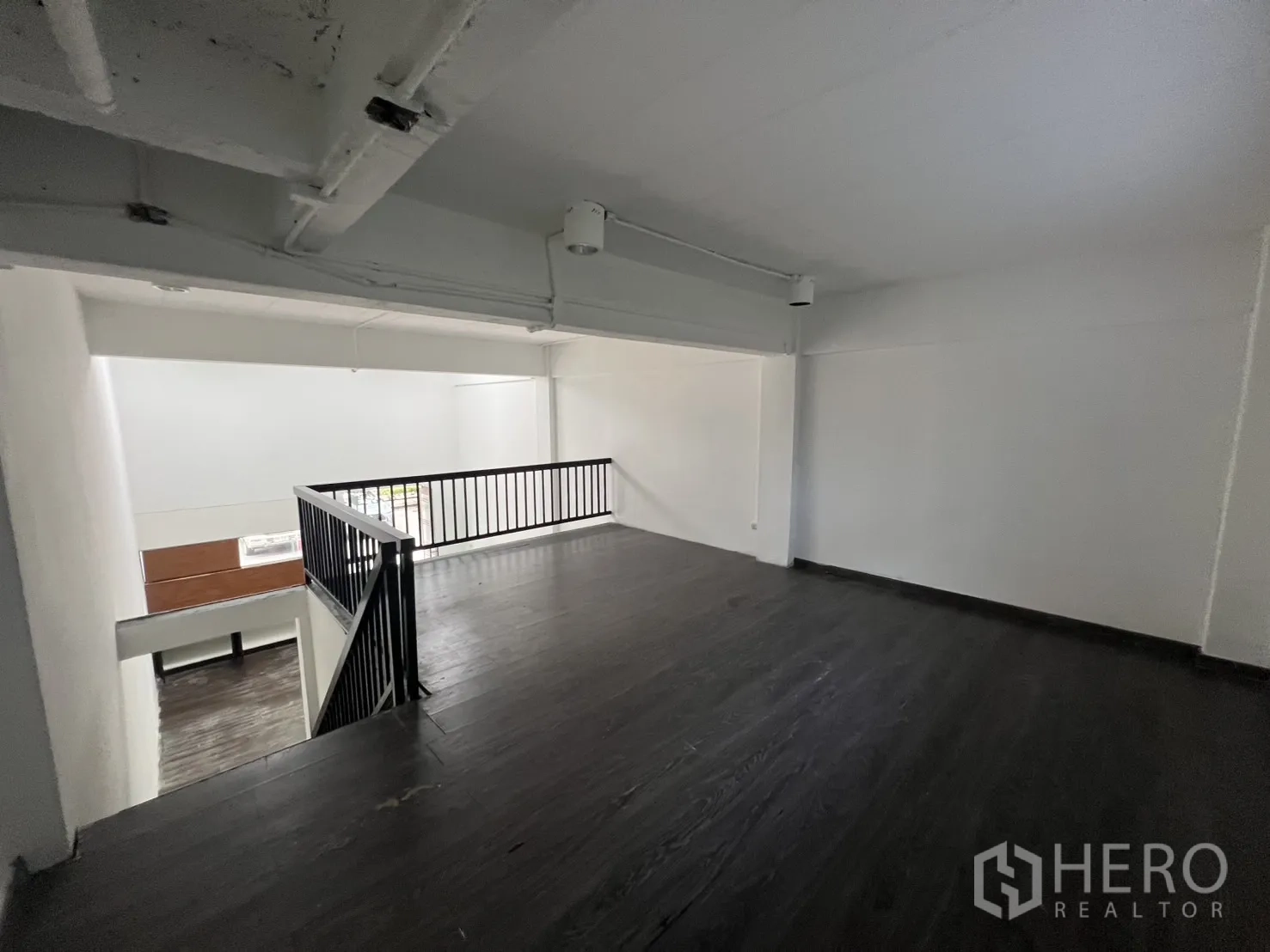 Retail Space for rent in Watthana, Bangkok - Mezzanine level with black metal railing overlooking the double-height retail area.