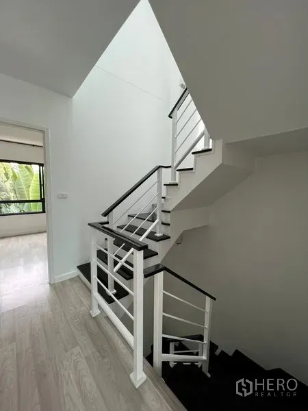Townhouse for sale in Bang Kapi, Bangkok - Modern white-and-black staircase with metal railing in a bright hallway.