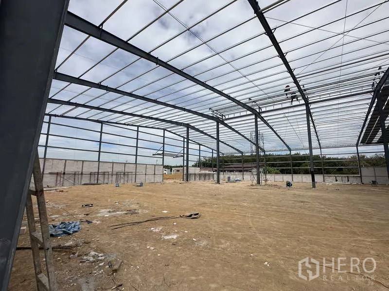 Warehouse for rent or sale in Nikhom Phatthana, Rayong - Angled interior view of the high-clear steel frame warehouse with perimeter wall.