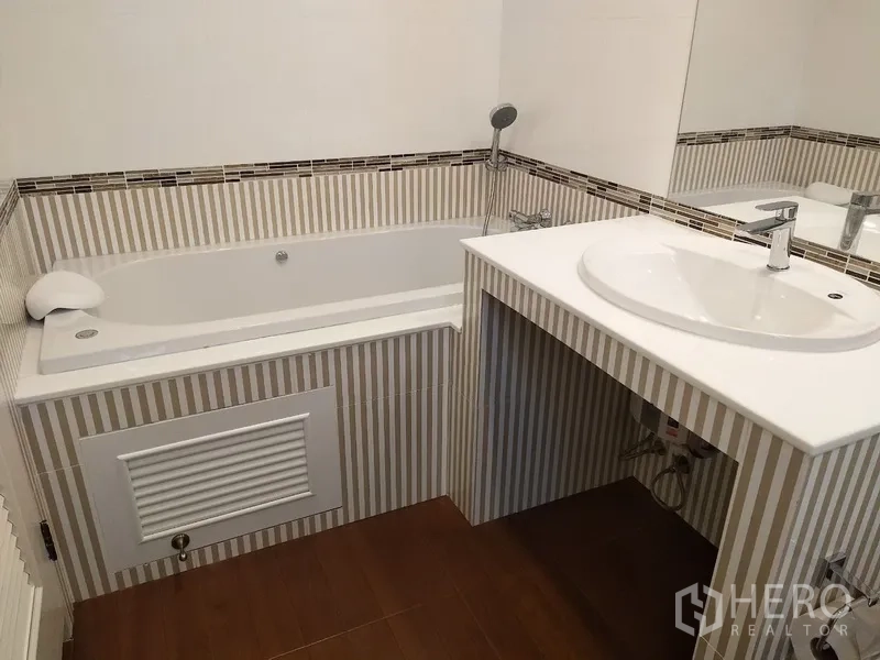 Townhouse for rent in Mueang Samut Prakan, Samut Prakan - Bathroom with built‑in bathtub and single‑sink vanity with mosaic trim.