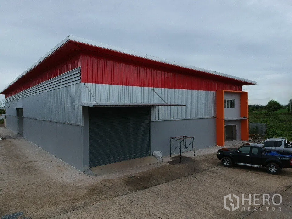 Warehouse for sale in Sai Noi, Nonthaburi - Metal-clad warehouse exterior with a large roller shutter, attached two-storey office wing, and driveway.