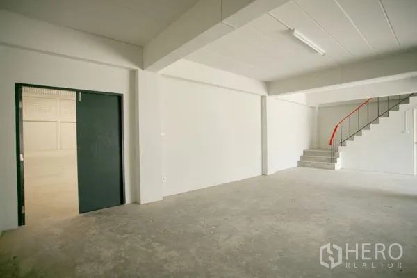 Warehouse for rent in Bang Phli, Samut Prakan - Ground-floor office area inside the warehouse with staircase to a mezzanine and a doorway to the main storage hall.