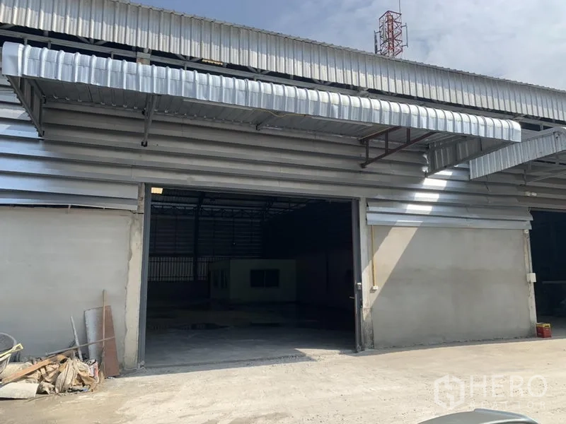 Warehouse for rent in Bueng Kum, Bangkok - Warehouse exterior with large roll-up door, metal awnings and a wide loading apron.