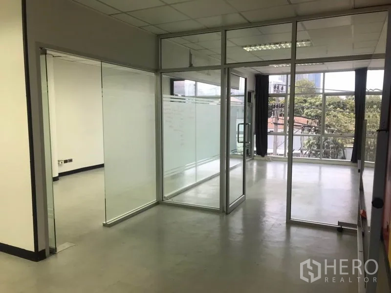 Office Space for rent in Khlong Toei, Bangkok - Corner office with multiple glass partitions and city and tree views through wide windows.