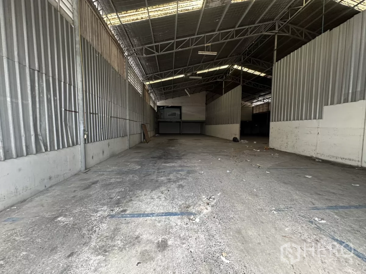 Warehouse for rent in Suan Luang, Bangkok - Deep storage bay with corrugated walls and marked floor lines.