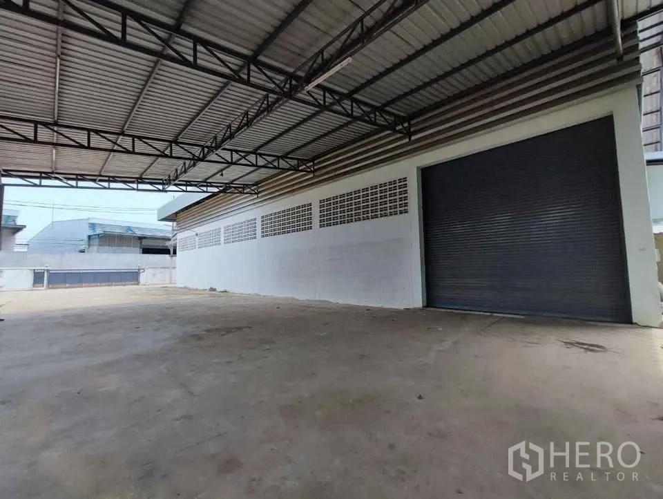 工厂 出租在Mueang Chachoengsao, Chachoengsao - 仓库前宽大的硬化雨棚区域和大卷闸门。