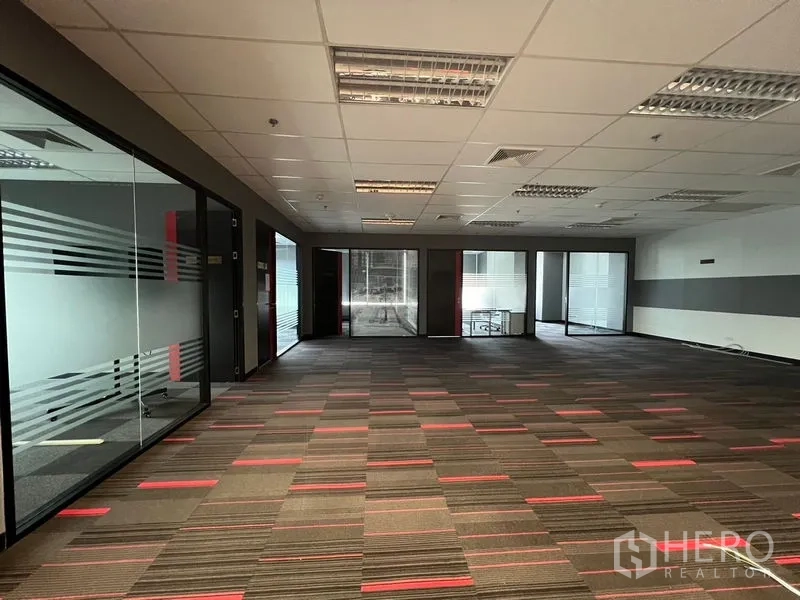 Office Space for rent in Huai Khwang, Bangkok - Large open workspace with striped carpet and glass-partitioned rooms.