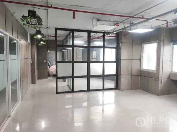 Office Space for rent in Watthana, Bangkok - Bright office zone showing a glass box meeting room and industrial ceiling lighting.