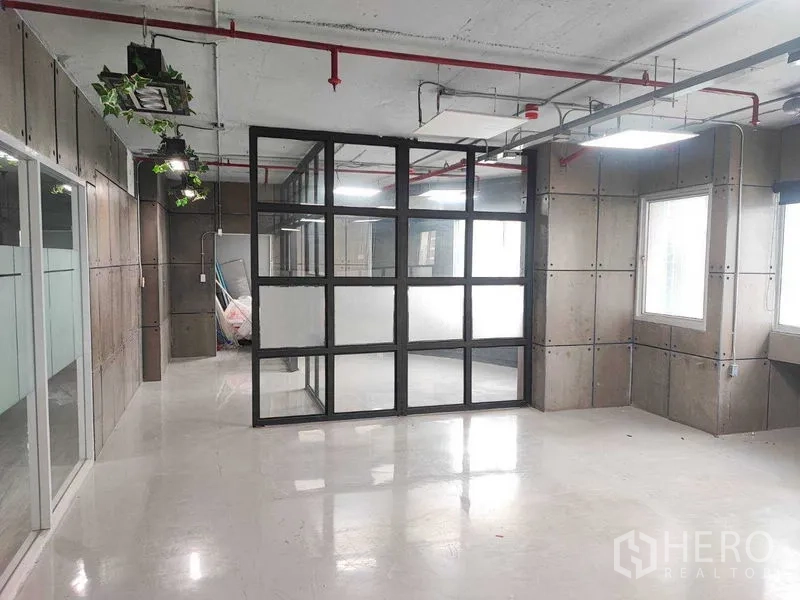 Office Space for rent in Watthana, Bangkok - Bright office zone showing a glass box meeting room and industrial ceiling lighting.
