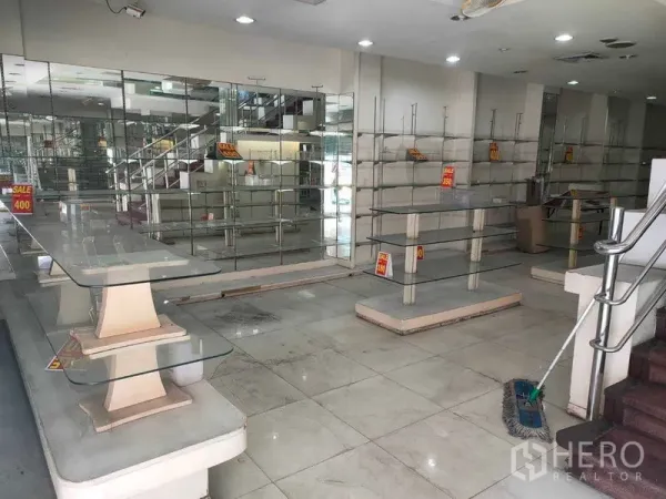 店屋 出租在Watthana, Bangkok - 一层零售区，设玻璃陈列架、镜面墙、瓷砖地面与楼梯。