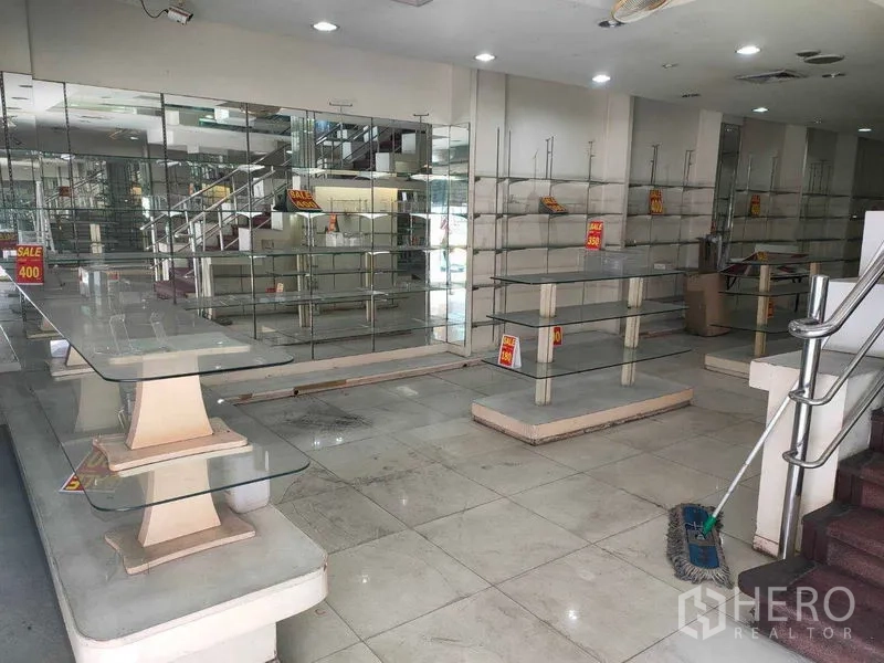 店屋 出租在Watthana, Bangkok - 一层零售区，设玻璃陈列架、镜面墙、瓷砖地面与楼梯。