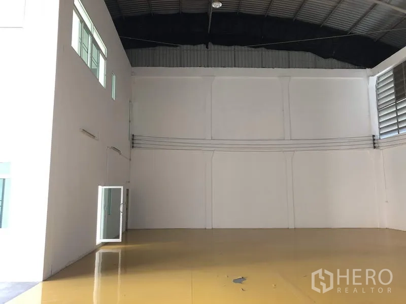 Factory for rent in Lam Luk Ka, Pathum Thani - Open clear‑span workspace with tall insulated roof and smooth epoxy floor finish.