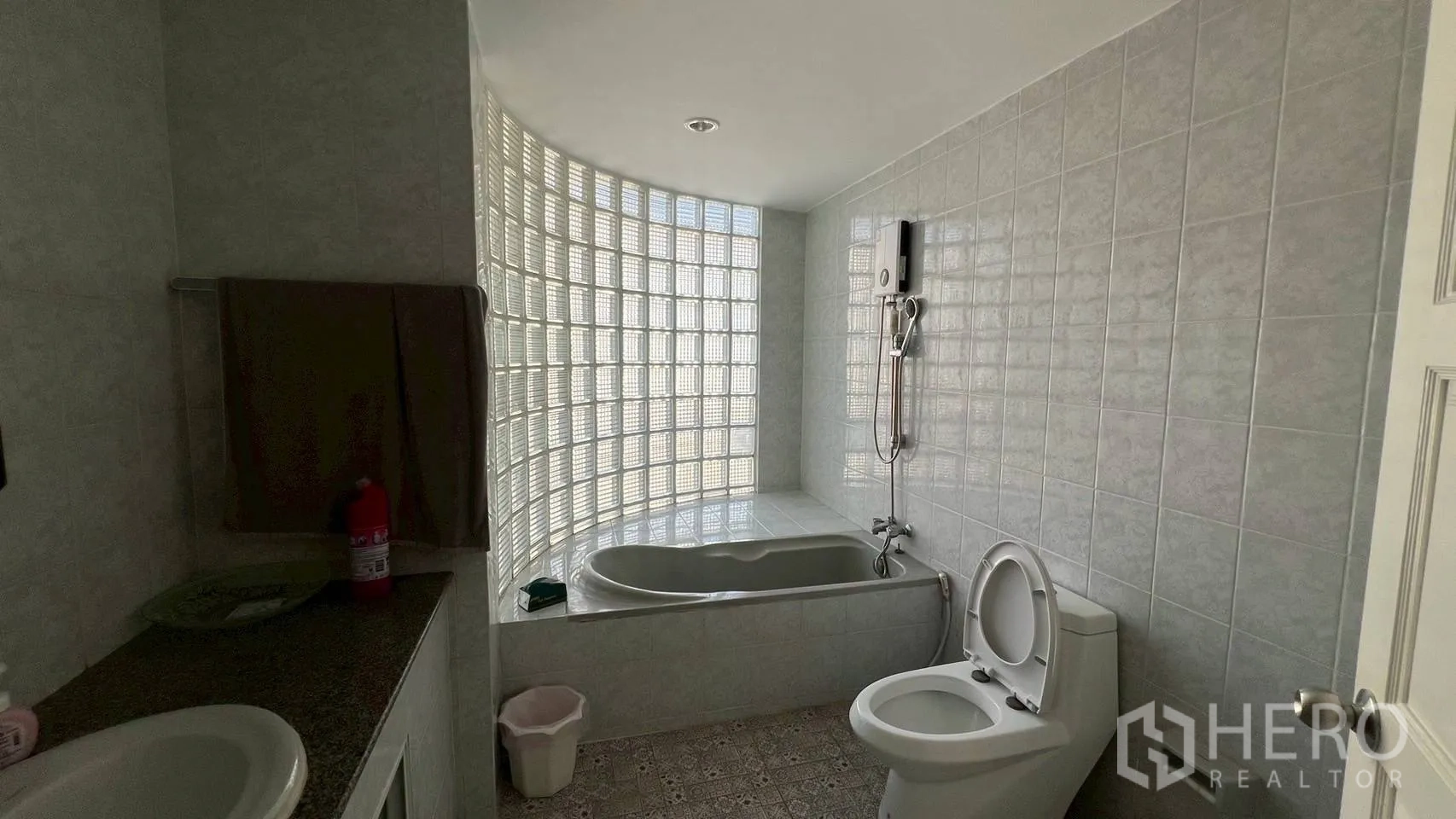Home Office for rent in Wang Thonglang, Bangkok - Bathroom with bathtub, shower, toilet and a curved glass-block window.