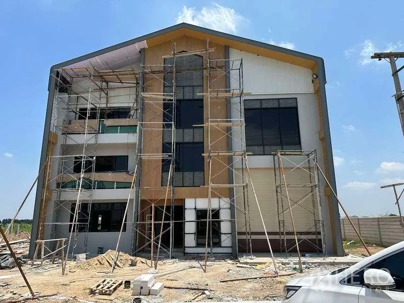工厂 出售在Khlong Luang, Pathum Thani - 正立面玻璃与卷门，仍在搭建脚手架。