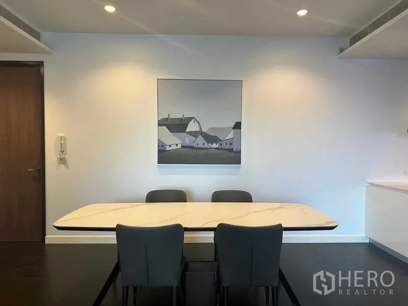Condominium for rent in Pathum Wan, Bangkok - Minimal dining corner with marble table and wall artwork.