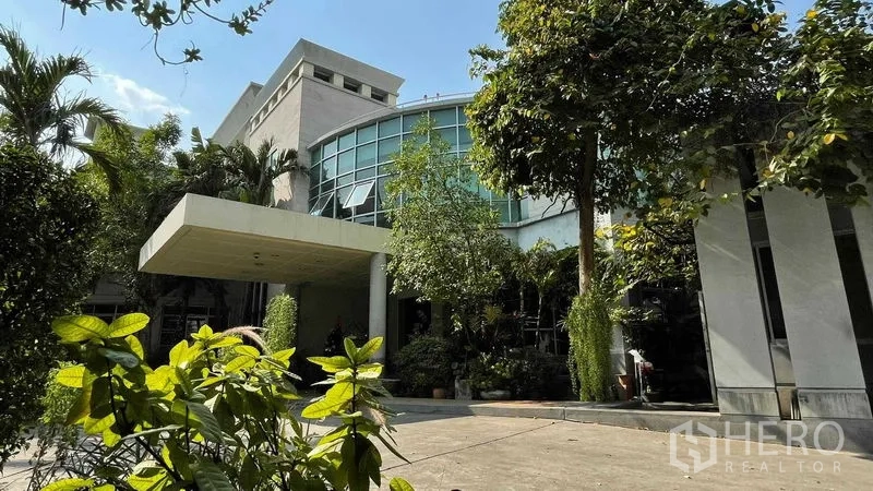 Warehouse for rent or sale in Bangkok Yai, Bangkok - Front exterior of the warehouse complex with landscaped plants and canopy entrance.