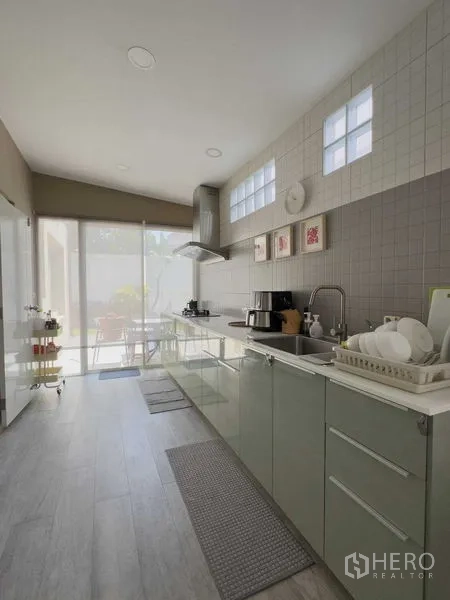 Detached House for rent or sale in Bang Khen, Bangkok - Modern galley kitchen with built-in cabinets, hood and glass door to the patio.