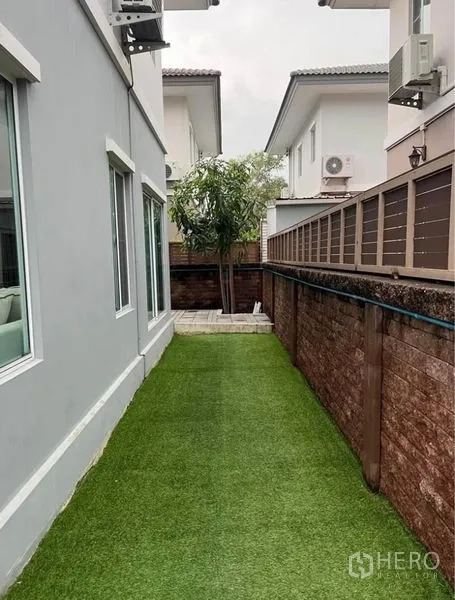 独立式住宅 出租在Suan Luang, Bangkok - 侧院狭长草坪，贴着围墙的人造草