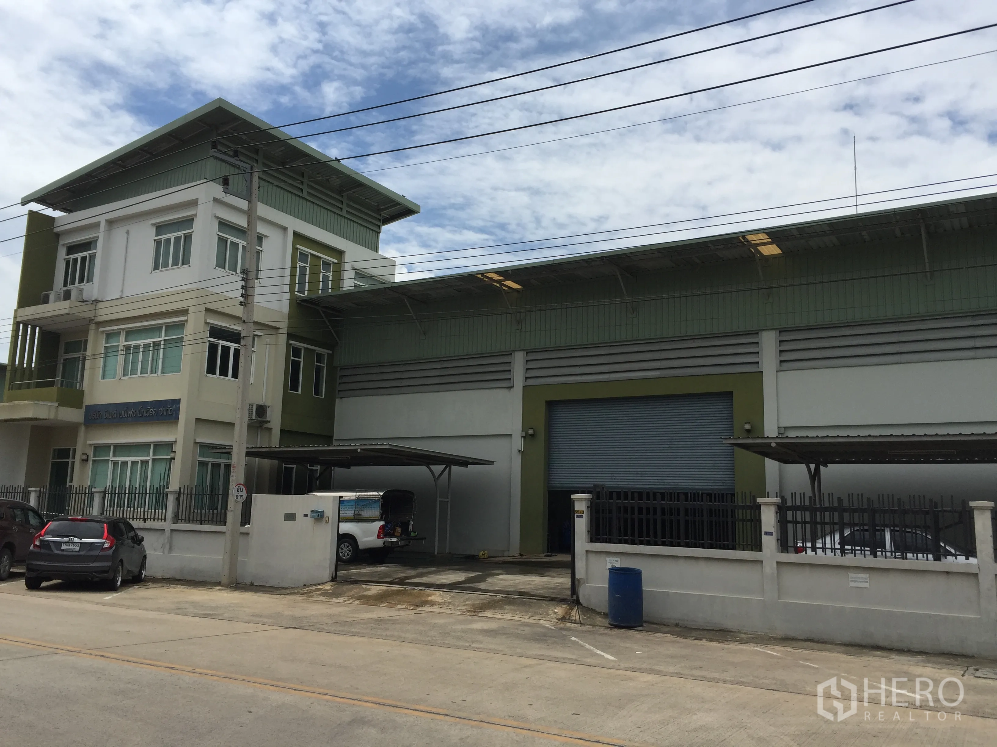 Factory for sale in Pathum Thani - Modern factory with attached three-storey office, wide roller shutter, covered loading bays and gated parking on a concrete road in Lam Luk Ka, Pathum Thani.