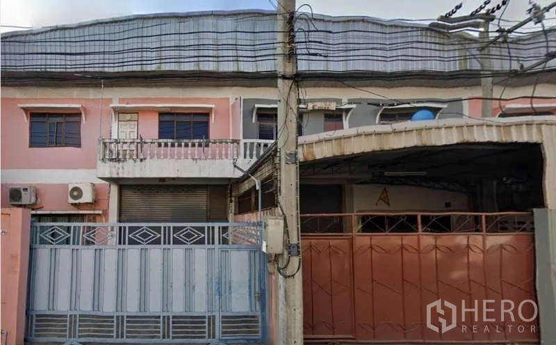 Warehouse for rent in Mueang Samut Sakhon, Samut Sakhon - Two-storey warehouse facade with pink exterior, balcony, roller shutter and wide steel gate.
