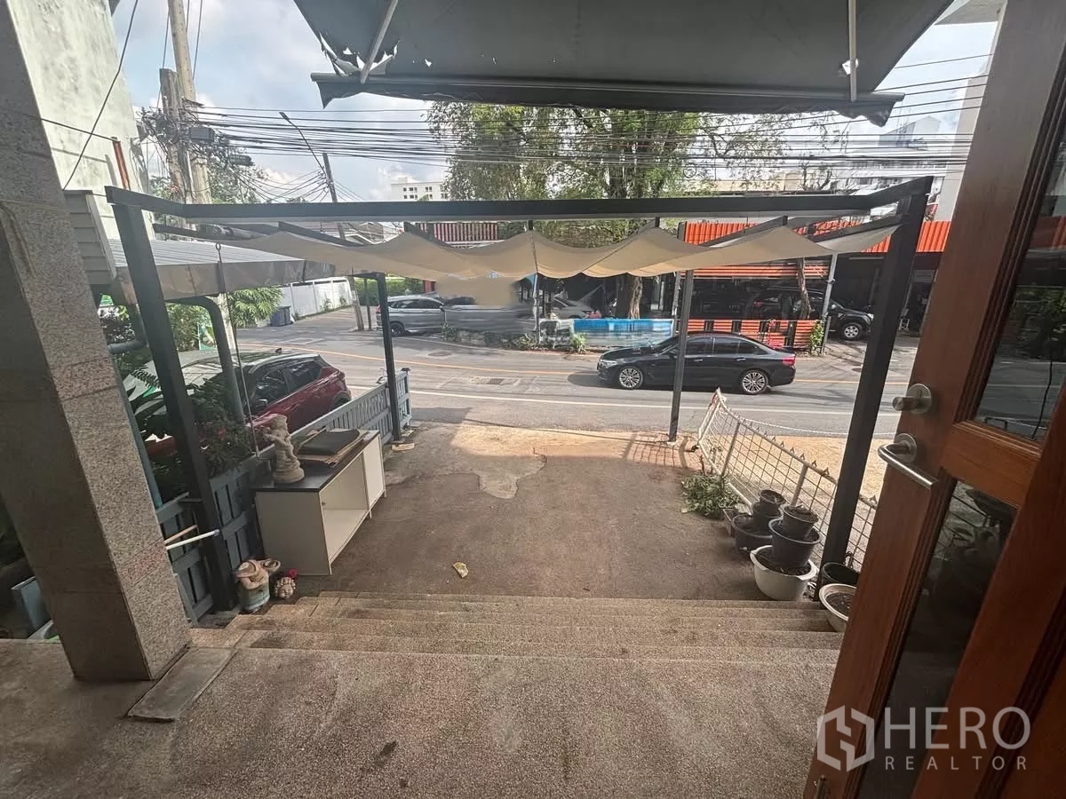 店屋 出租在Watthana, Bangkok - 带遮棚的前露台与台阶，可眺望街道与车辆。