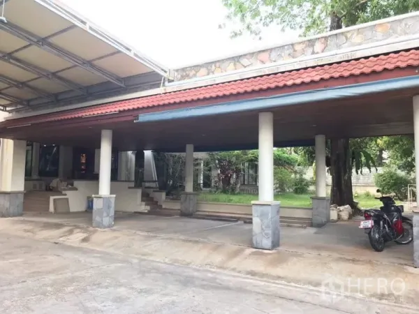 Detached House for rent in Bang Phli, Samut Prakan - Large covered carport with tiled roof, columns and driveway beside a small lawn.